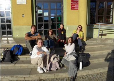 Six students sitting on a staircase in the sun in the city of Wroclaw. 